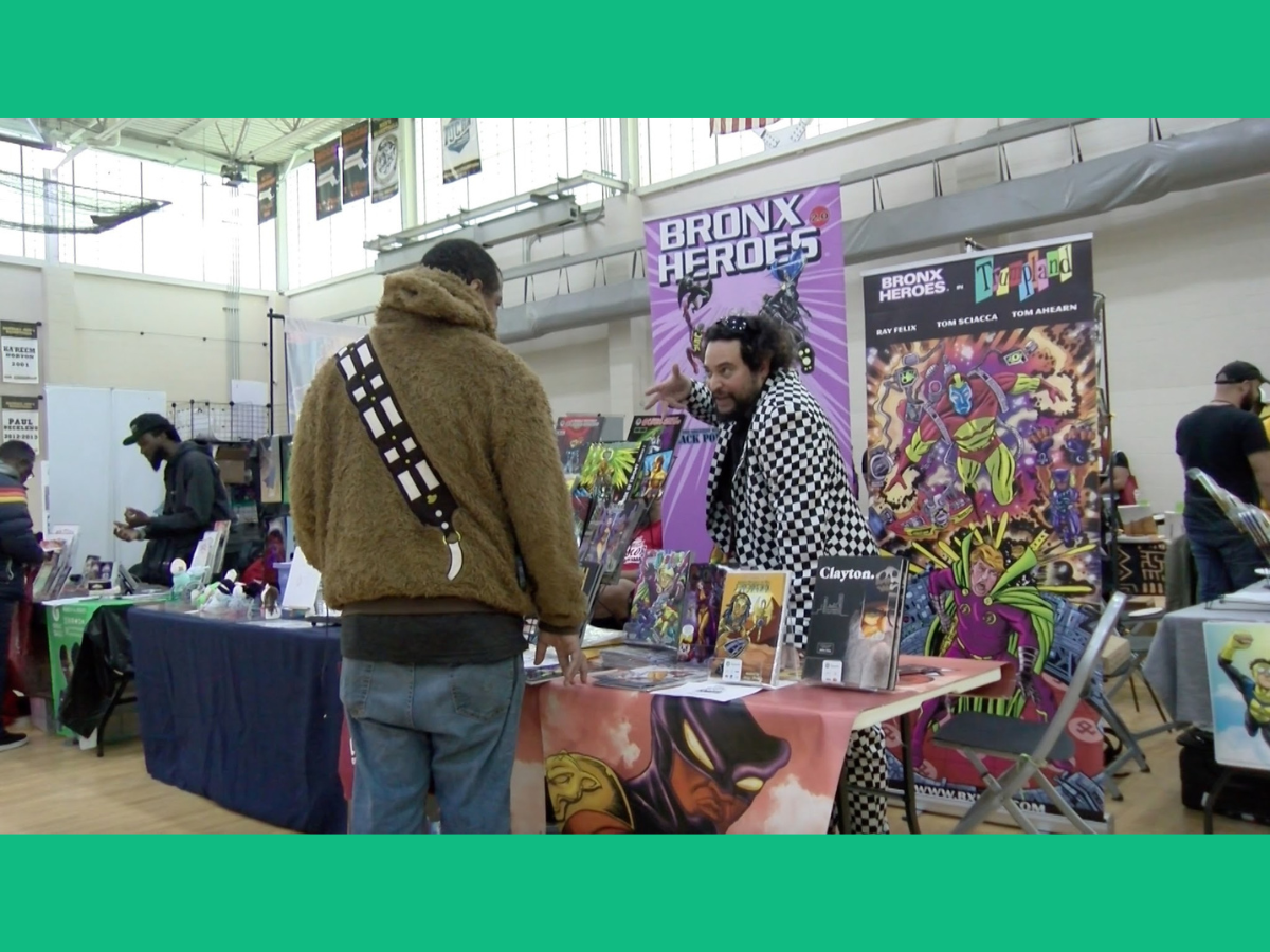 Ray Felix talks to a fan at the 2026 Boston Comics in Color Festival. Photo by Mattea Ortiz. Copyright 2026 Mattea Ortiz. Used with permission.