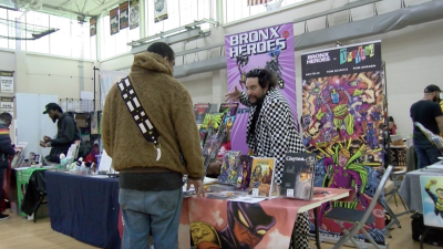 Ray Felix talks to a fan at the 2026 Boston Comics in Color Festival. Photo by Mattea Ortiz. Copyright 2026 Mattea Ortiz. Used with permission.